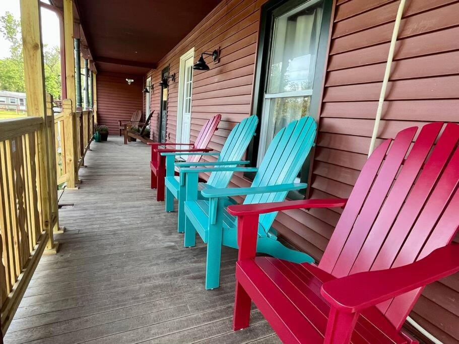 una fila de sillas coloridas sentadas en un porche en 5 Bed / 3 bath Apt Near Jiminy Peak Berkshires, en Stephentown