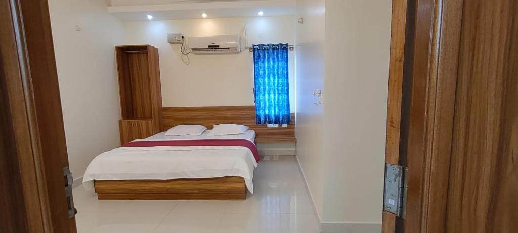 um pequeno quarto com uma cama e uma janela em Shree Skanthas inn em Palni