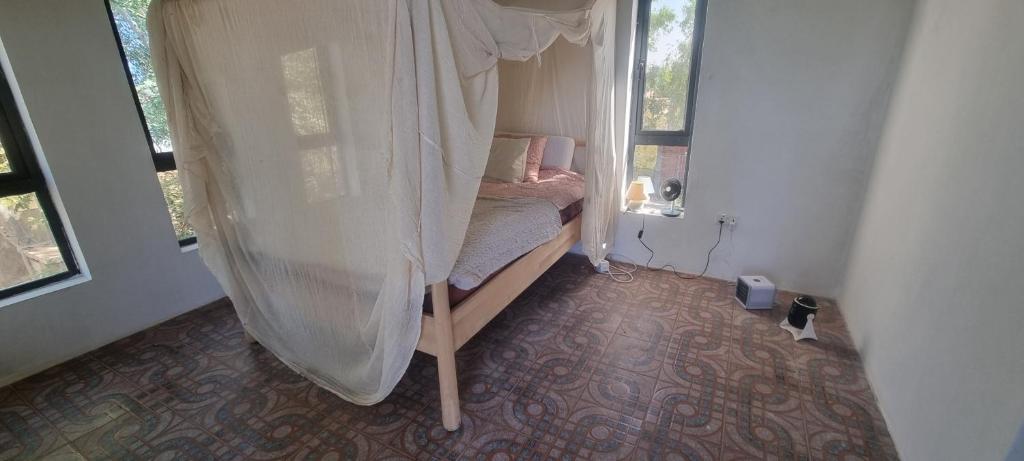 a small bedroom with a bed with a canopy at E House in Brufut