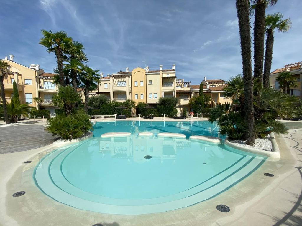 una grande piscina con palme e edifici di Le Residenze Mediterranee Apartments a Lido di Jesolo