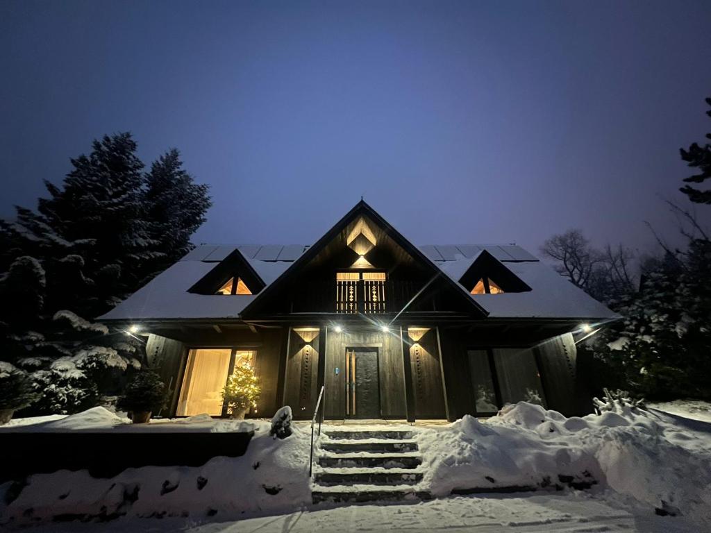 a house covered in snow at night with lights at Chalet V11 by Villa 11 Folk & Design in Zakopane