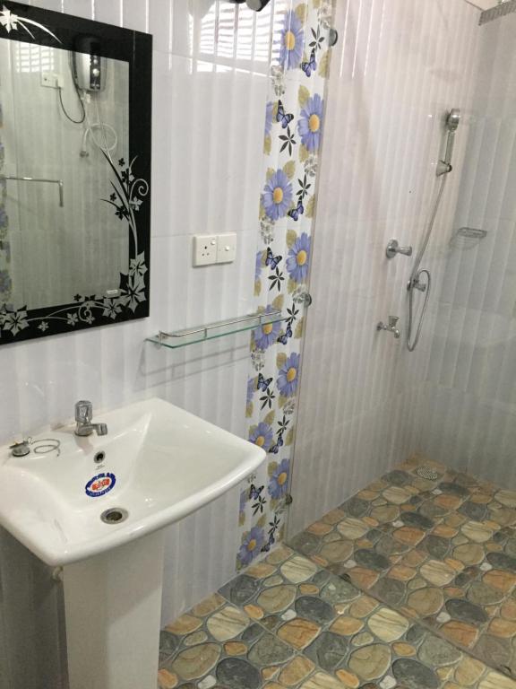 La salle de bains blanche est pourvue d'un lavabo et d'une douche. dans l'établissement Elephants Safari Cottages, à Uda Walawe