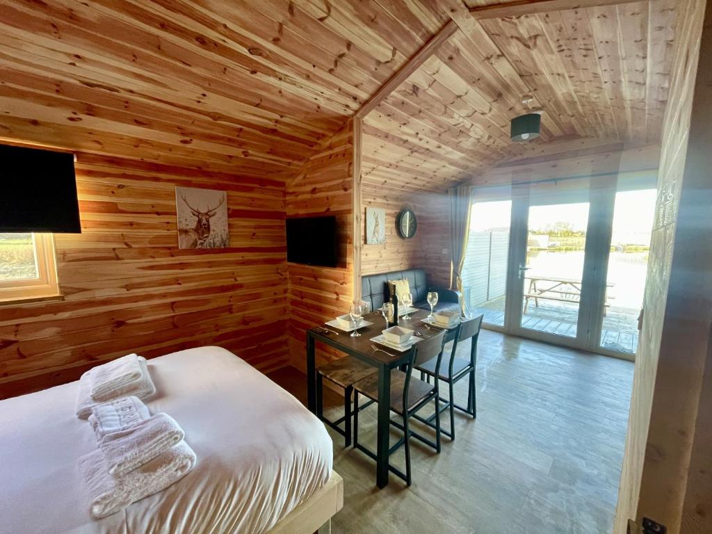 a bedroom with a bed and a desk in a room with wooden walls at Lakeside Fishing Retreats in Boston