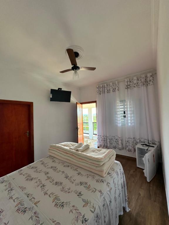 a bedroom with a bed and a ceiling fan at Suítes 4 Estações in São Thomé das Letras