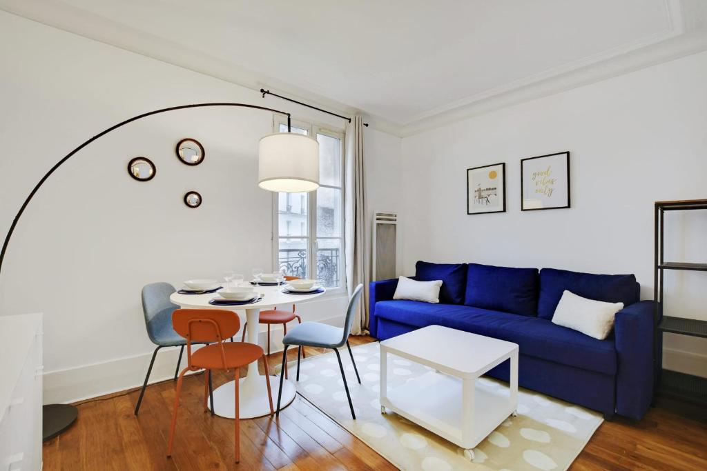 Cozy Parisian Retreat in the Heart of the City في باريس: غرفة معيشة مع أريكة زرقاء وطاولة