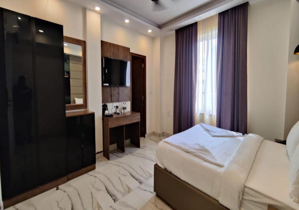 ein Hotelzimmer mit einem Bett und einem TV in der Unterkunft PK Boutique Hotel in Noida