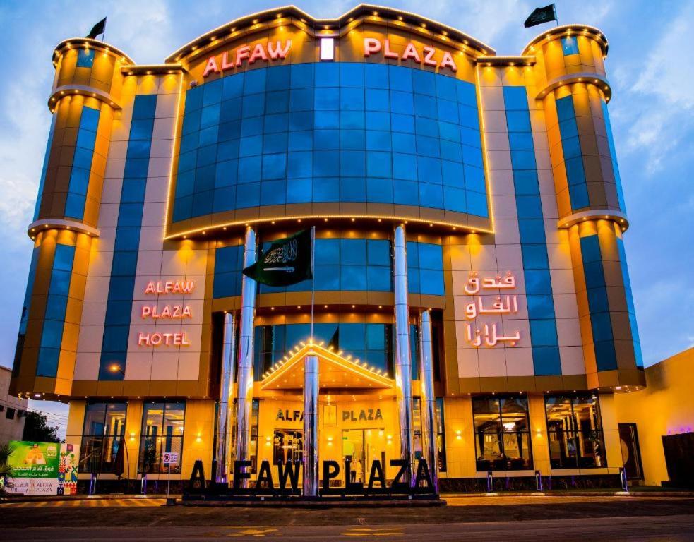a large building with neon signs in front of it at HOTEL ALFAW PLAZA in Sharurah