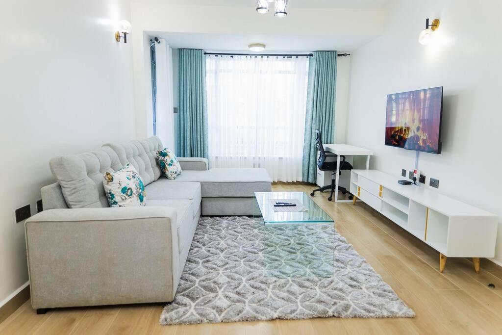 uma sala de estar com um sofá e uma mesa em Urban Living 2Br Westlands, King & Queen size Beds em Nairobi