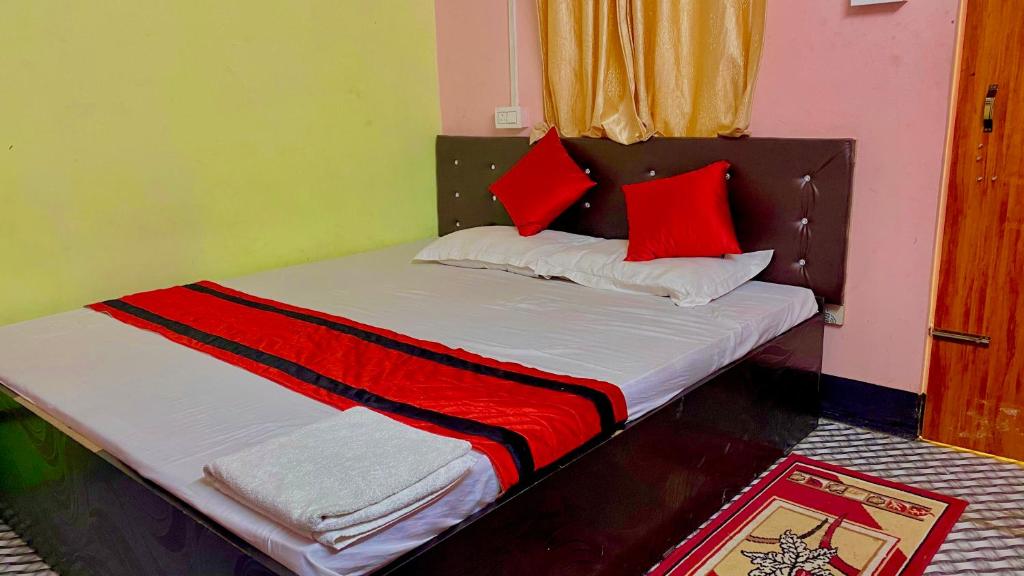 a bed with red and white pillows on it at Sweet Home Lodge in Guwahati