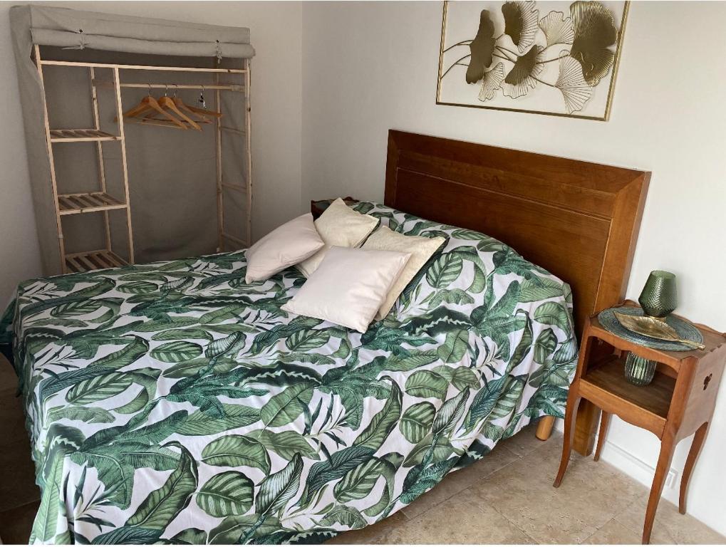 a bedroom with a bed with a green and white comforter at Dépendance de charme in Pia