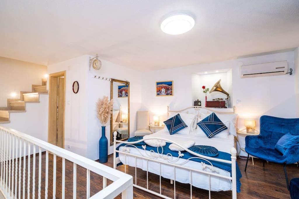 a white bedroom with a bed and a blue chair at Plaza Royal in the centre in Dubrovnik