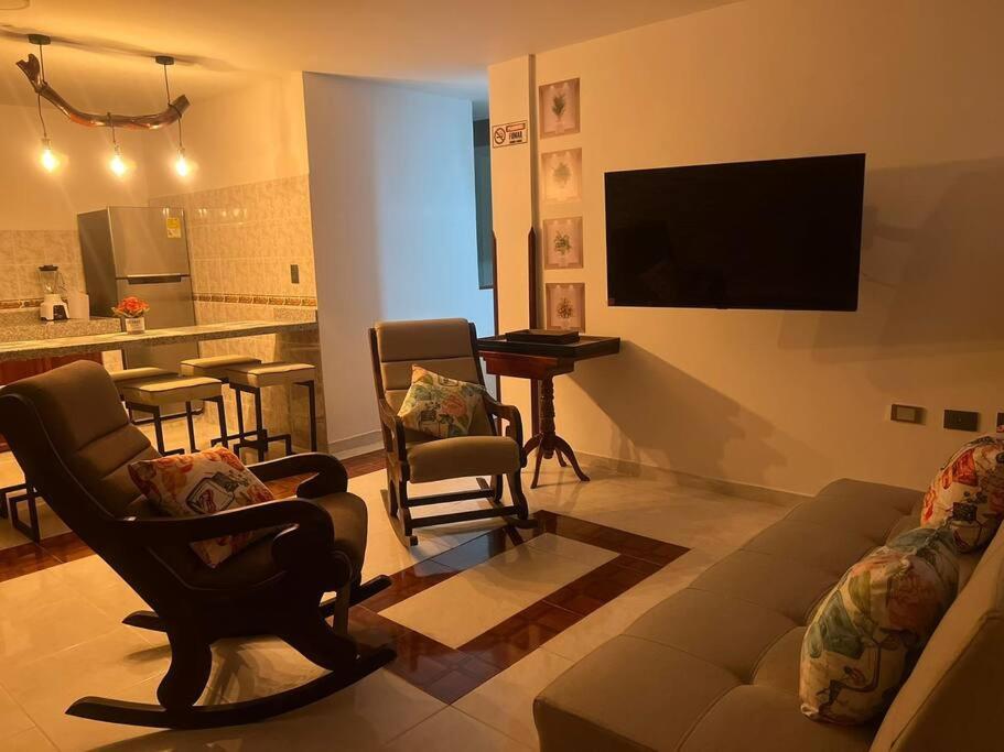 uma sala de estar com um sofá e cadeiras e uma televisão em Casa bonita en San Gil em San Gil