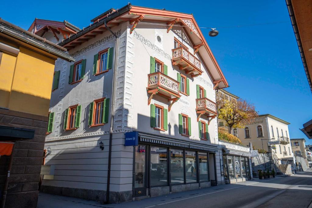 ein weißes Gebäude mit bunten Fenstern auf einer Straße in der Unterkunft Villa Hartenfels 3 in Scuol