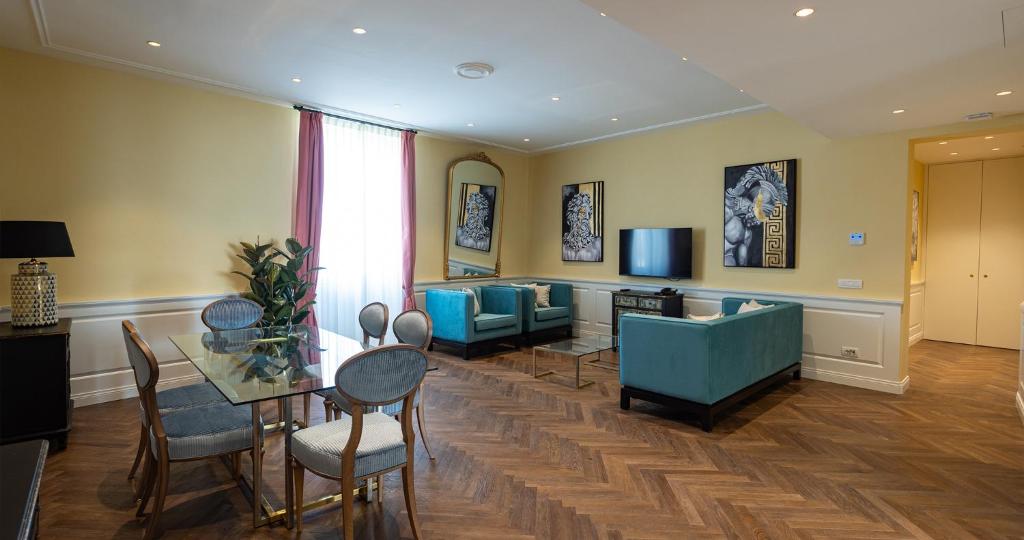 Algilà Firenze Luxury Apartments في فلورنسا: غرفة معيشة مع طاولة وكراسي وتلفزيون