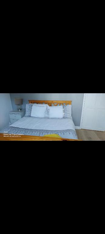 uma cama com lençóis brancos e almofadas num quarto em Stes place em Liverpool