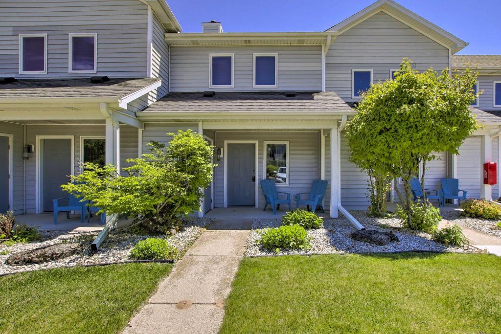 a house with blue chairs in the front yard at Door County Getaway - Walk to State Park! in Fish Creek