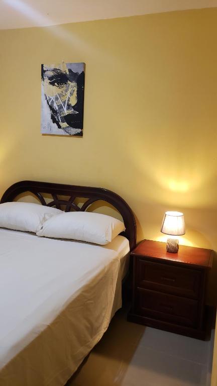 ein Schlafzimmer mit einem Bett und einem Tisch mit einer Lampe in der Unterkunft Petite Lounge in Los Paredones