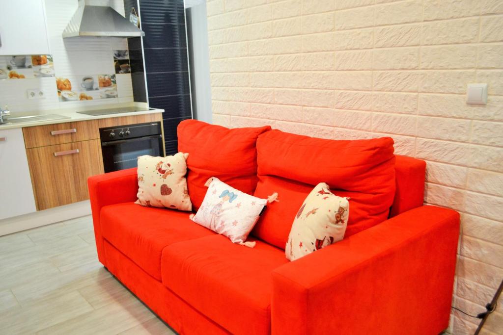 eine orangefarbene Couch mit Kissen darauf in der Küche in der Unterkunft Apartamentos Garage Centro in Málaga
