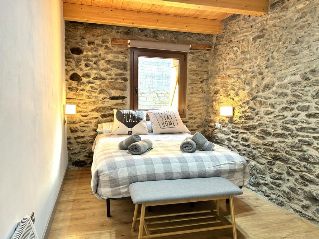1 dormitorio con cama y pared de piedra en Casa de muntanya i familiar amb llar de foc by RURAL D'ÀNEU, en Escaló