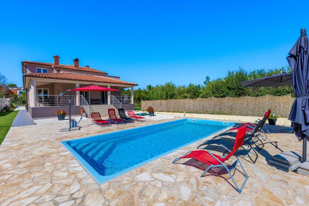 uma piscina com cadeiras e uma casa em Ana em Ližnjan