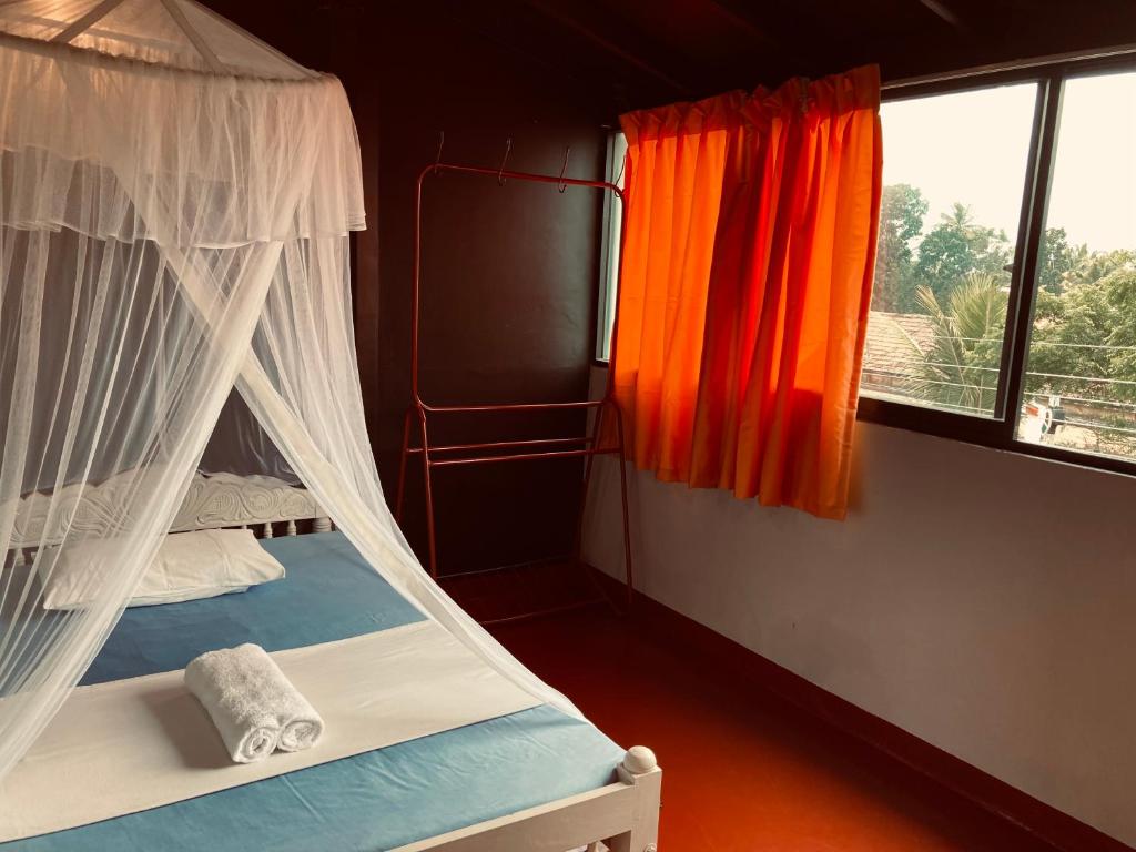 a bedroom with a bed with a canopy and a window at Railway Hostel in Matara