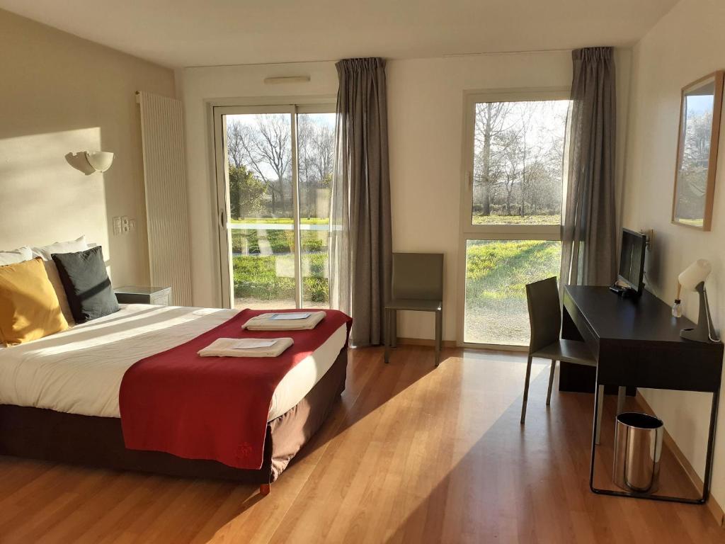 um quarto com uma cama, uma secretária e janelas em La Villa des Golf.e.s em Theix