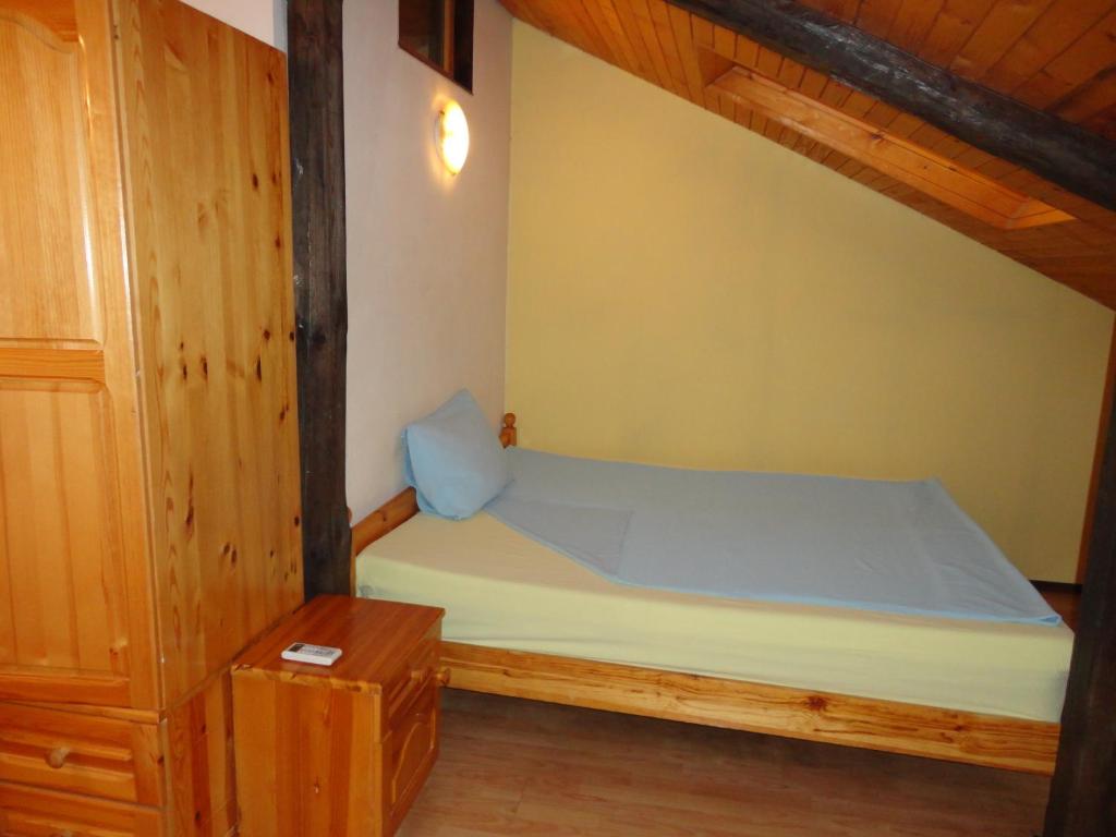 um pequeno quarto com uma cama e um armário de madeira em Guest House The House em Veliko Tarnovo