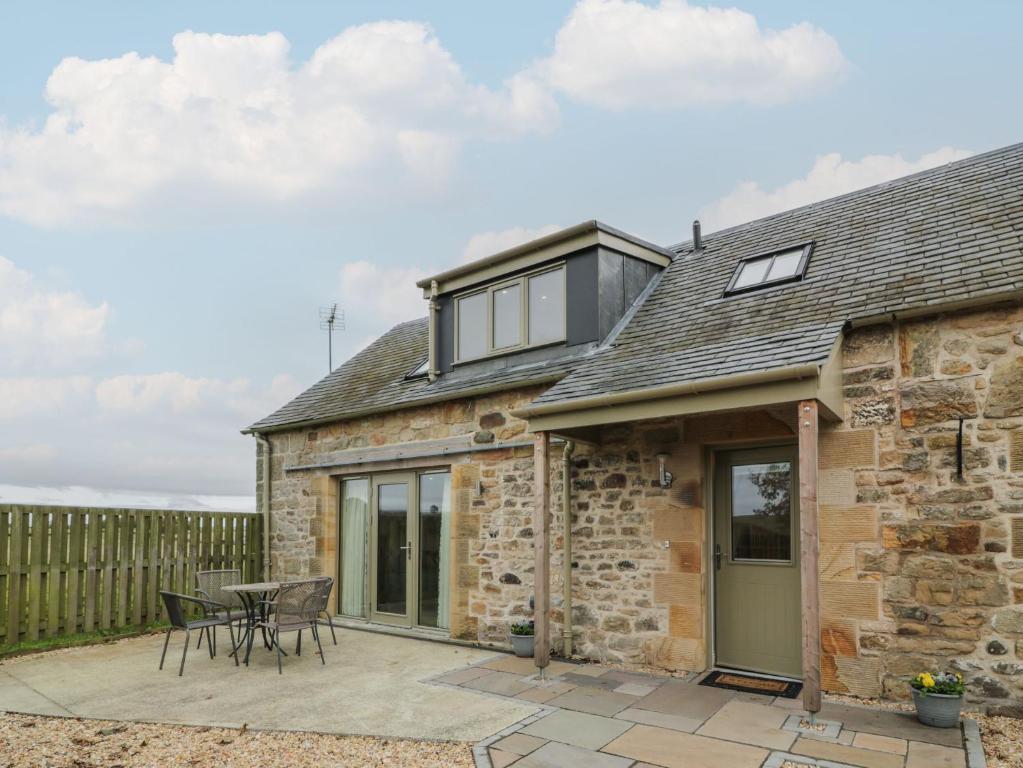 an extension to a stone cottage with a patio at Thorneydyke Cottage in Stirling