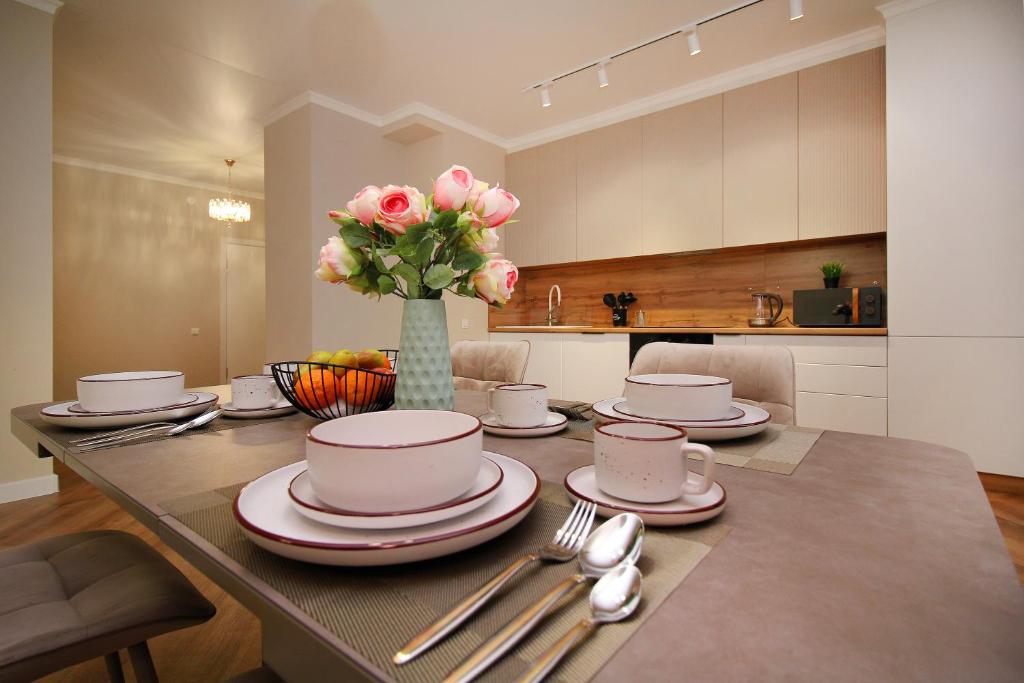 a dining room table with a vase of pink roses at Modern, Spacious and Elegant Apt in Almaty