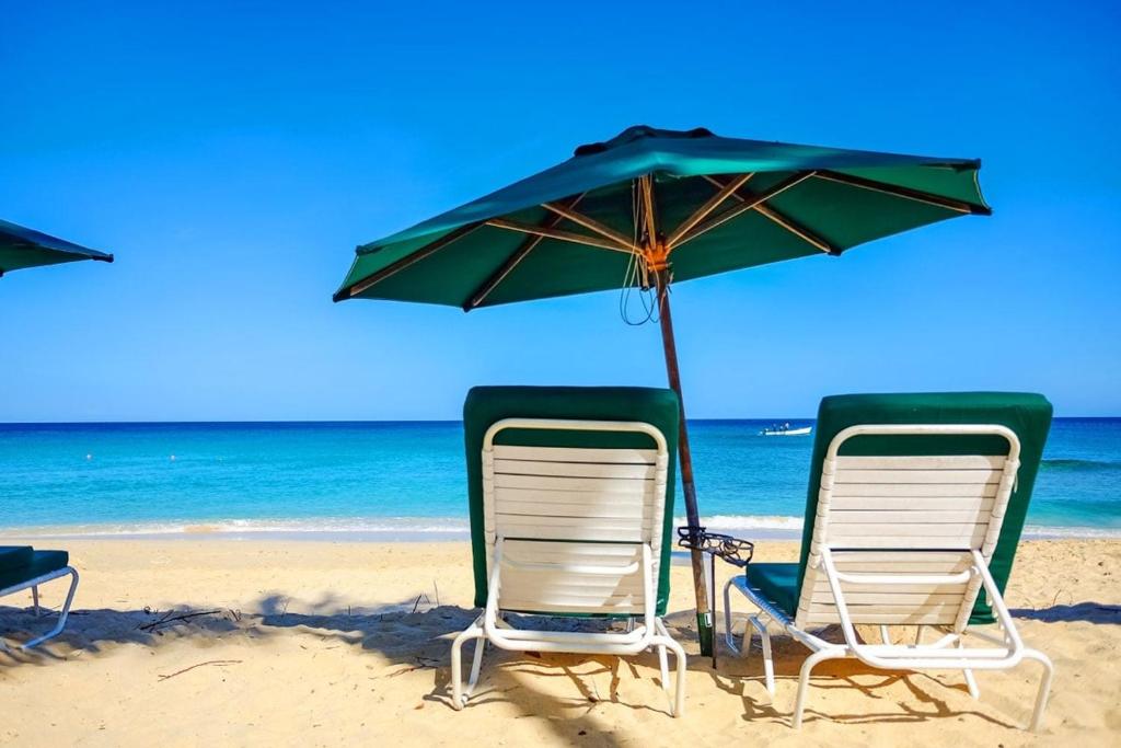 - deux chaises et un parasol sur une plage dans l'établissement Condos at Glitter Bay Estate by Blue Sky Luxury, à Saint James