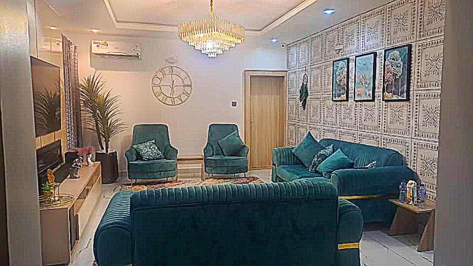 a living room with a blue couch and two chairs at Luxury 4 Bdr Home in the city in Abuja