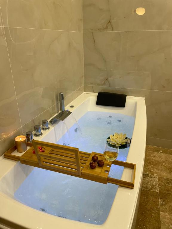 una vasca idromassaggio con un vassoio di legno in un bagno di Villa Segny a Ségny