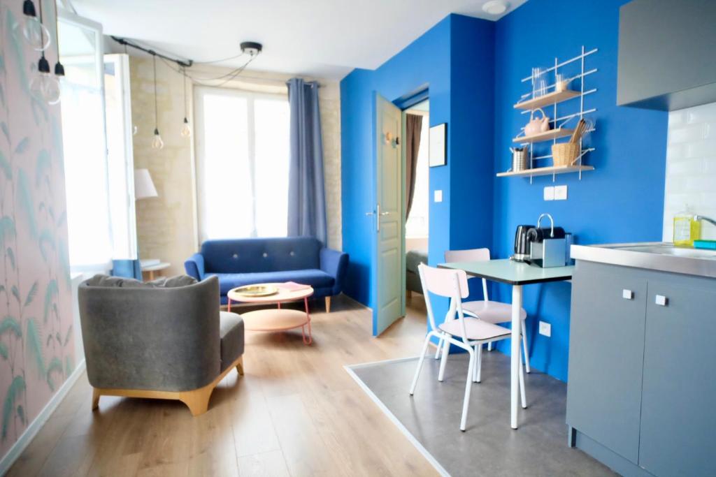 un soggiorno con pareti blu e tavolo e sedie di La Company Des Concierges : La Bonbonnière a Caen