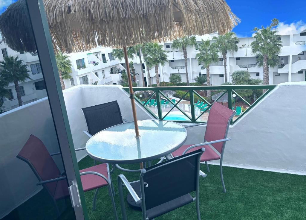 una mesa con sillas y una sombrilla en el balcón en Bella Vista 414-Ocean Lanzamar- Puerto Del Carmen en Tías