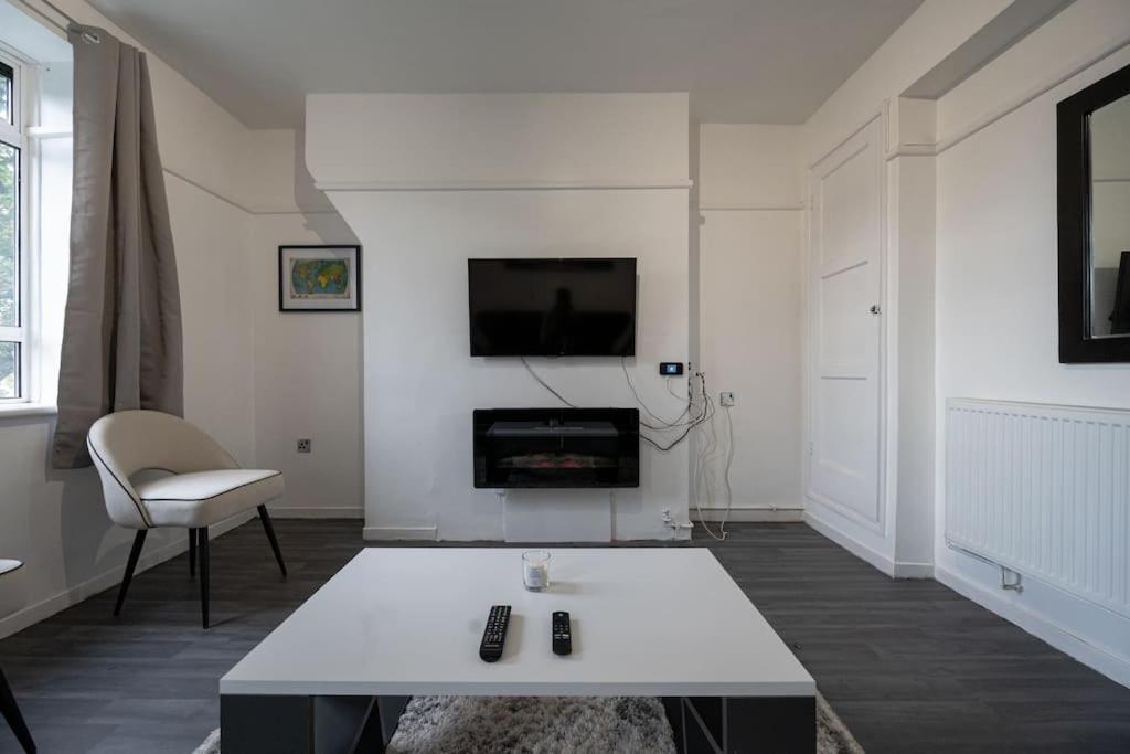 a white living room with a table and a tv at Stunning apartment in Dulwich in London