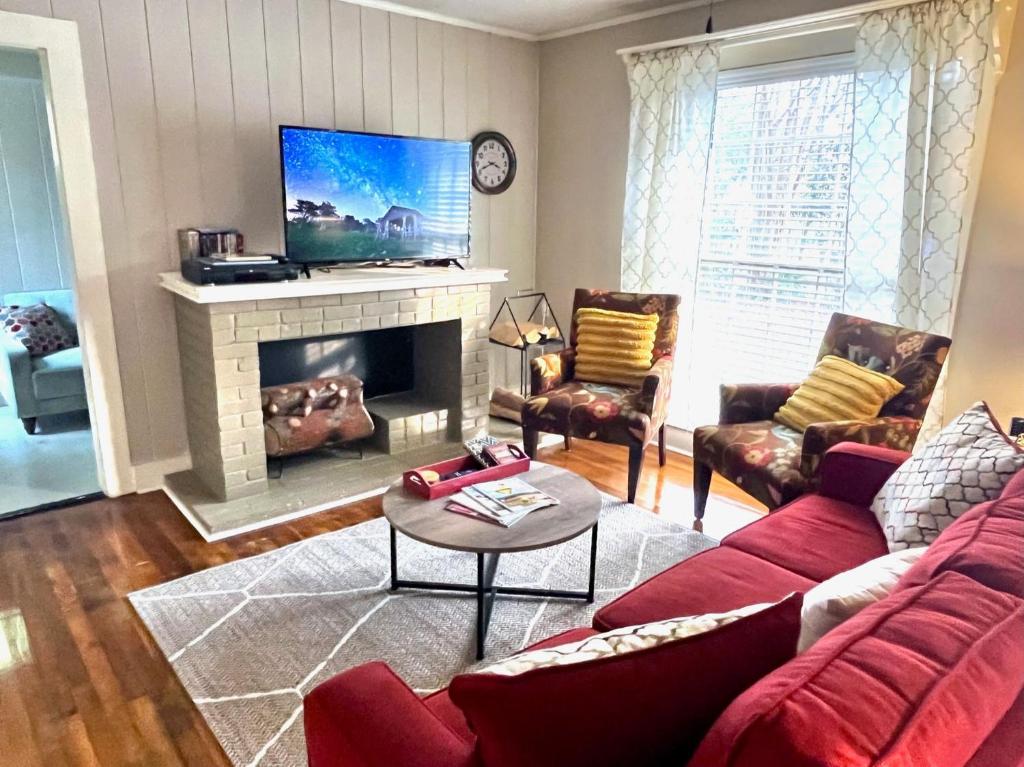 a living room with a red couch and a fireplace at KING BED Family Friendly Cottage - Walk to Zoo & Waterpark - Near Downtown & Midtown in Hattiesburg