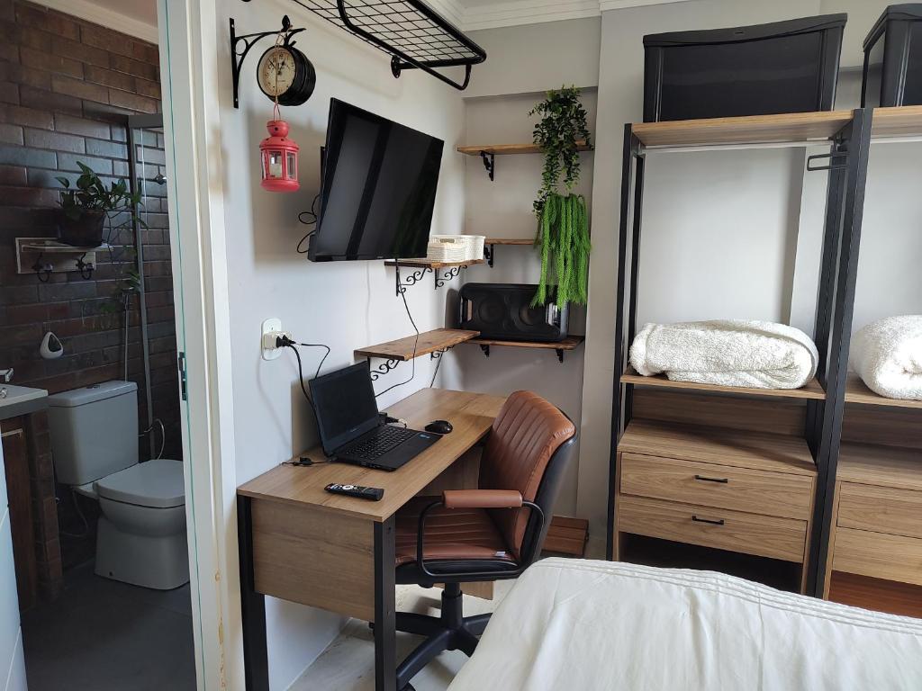 Schlafzimmer mit einem Schreibtisch, einem Laptop und einem Bett in der Unterkunft Rota Beach-Aeroporto l ortobom queen l ar cond l tv smart l wi-fi l cozinha completa in Maceió