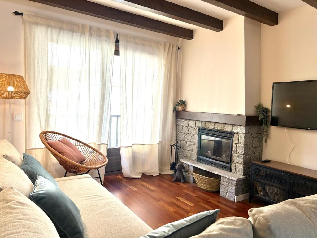 ein Wohnzimmer mit einem Sofa und einem Kamin in der Unterkunft Apartament encantador i cèntric amb llar de foc by RURAL D'ÀNEU in Esterri d'Àneu