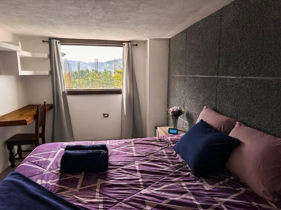 een slaapkamer met een paars bed en een raam bij Casa Espaciosa in Quetzaltenango