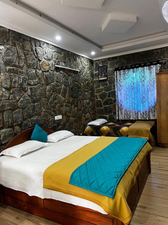 a bedroom with a large bed with a stone wall at Vaga Copper Castle in Vagamon