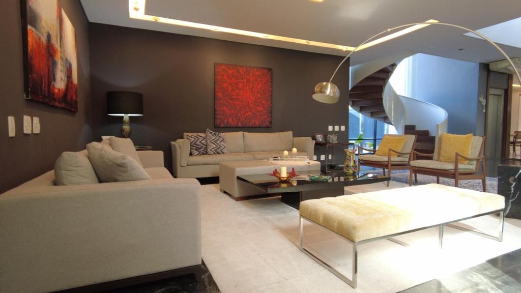 uma sala de estar com sofás e cadeiras e uma escadaria em CASA BARRA DA TIJUCA no Rio de Janeiro