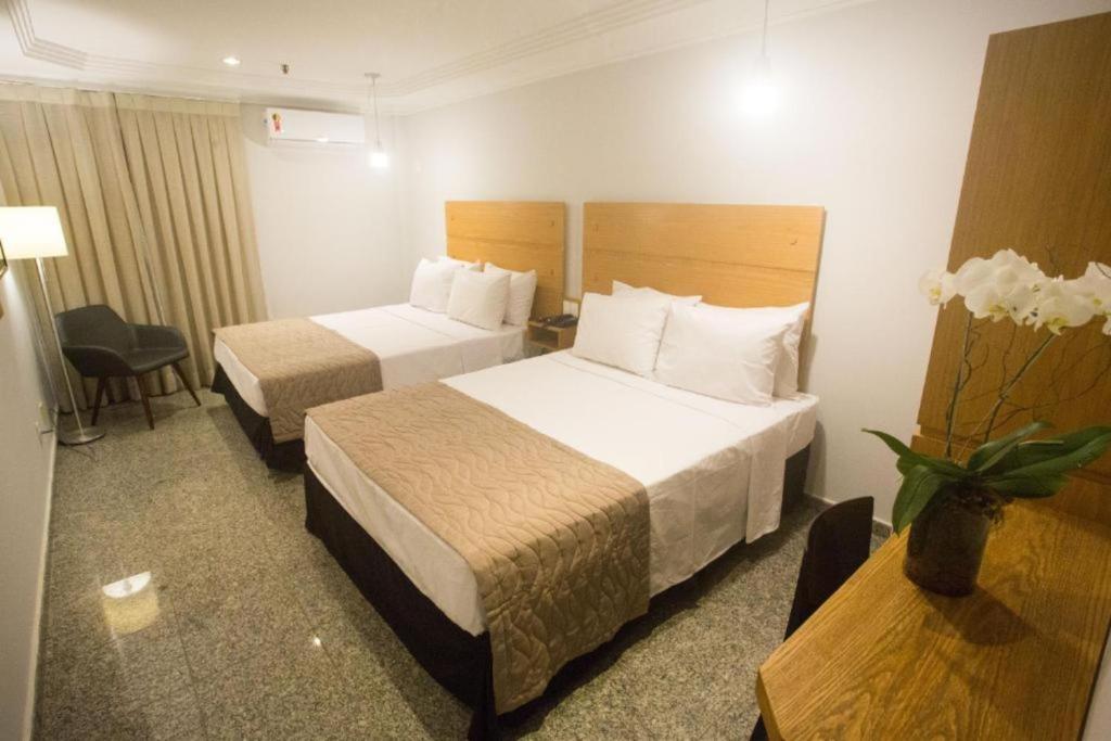 um quarto de hotel com duas camas e uma mesa em Regency Copacabana Hotel no Rio de Janeiro