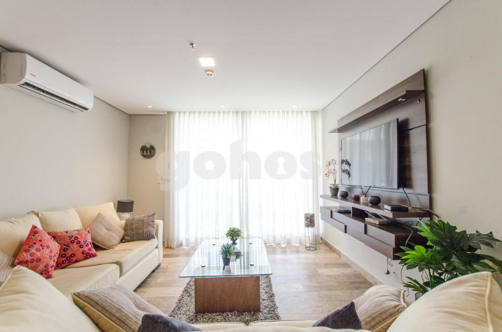 sala de estar con sofá y TV en Spacious 2 Bedroom Villa Morra Apartment, en Asunción