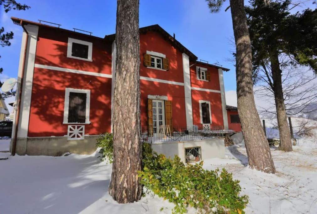 a red house with trees in the snow at Antico Chalet Momosa Maxi in Ovindoli