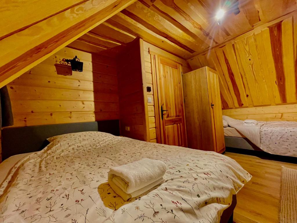 a bedroom with a bed in a wooden cabin at Domki Na Wypasie Jacuzzi & Sauna in Białka Tatrzanska