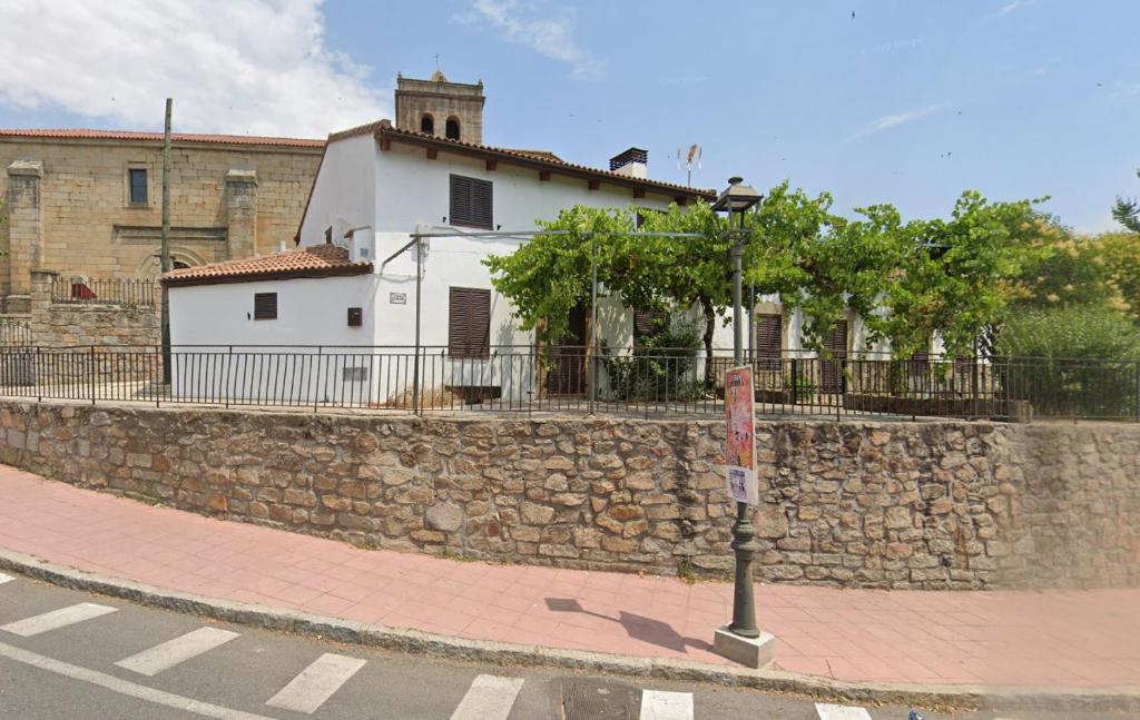 a building behind a stone wall next to a street at Villa Revolcona in La Adrada