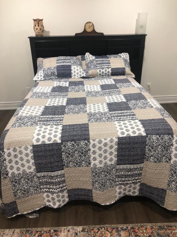 a bed with a black and white quilt on it at Home from Home! in Brampton