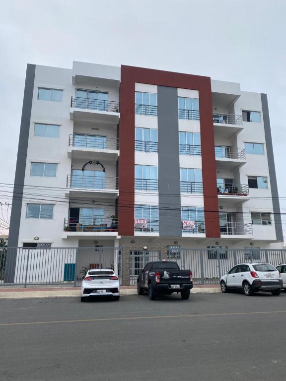 a large building with cars parked in a parking lot at Kattyapartament Chipipe Salinas in Salinas