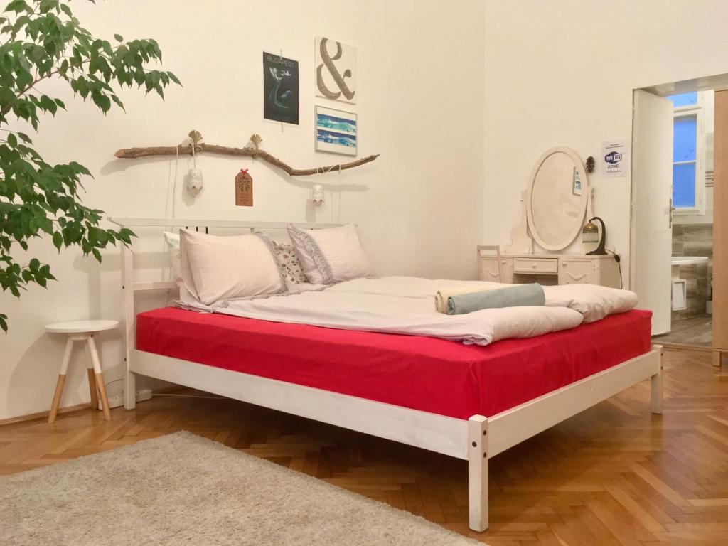 um quarto com uma cama com um cobertor vermelho e um espelho em Gaia Hostel em Budapeste