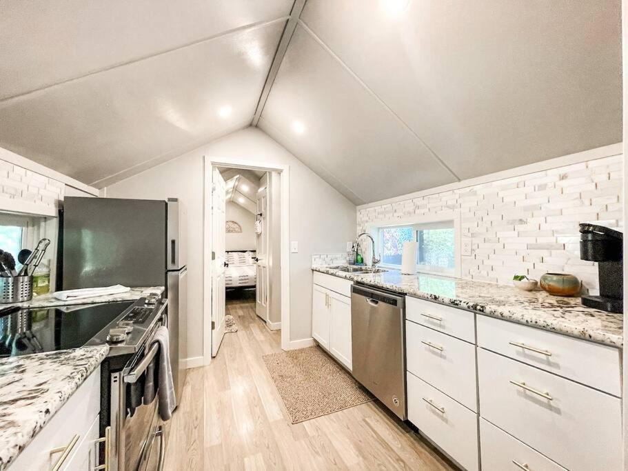 a kitchen with white cabinets and a black refrigerator at Cozy cottage in the heart of COS - pet friendly in Colorado Springs